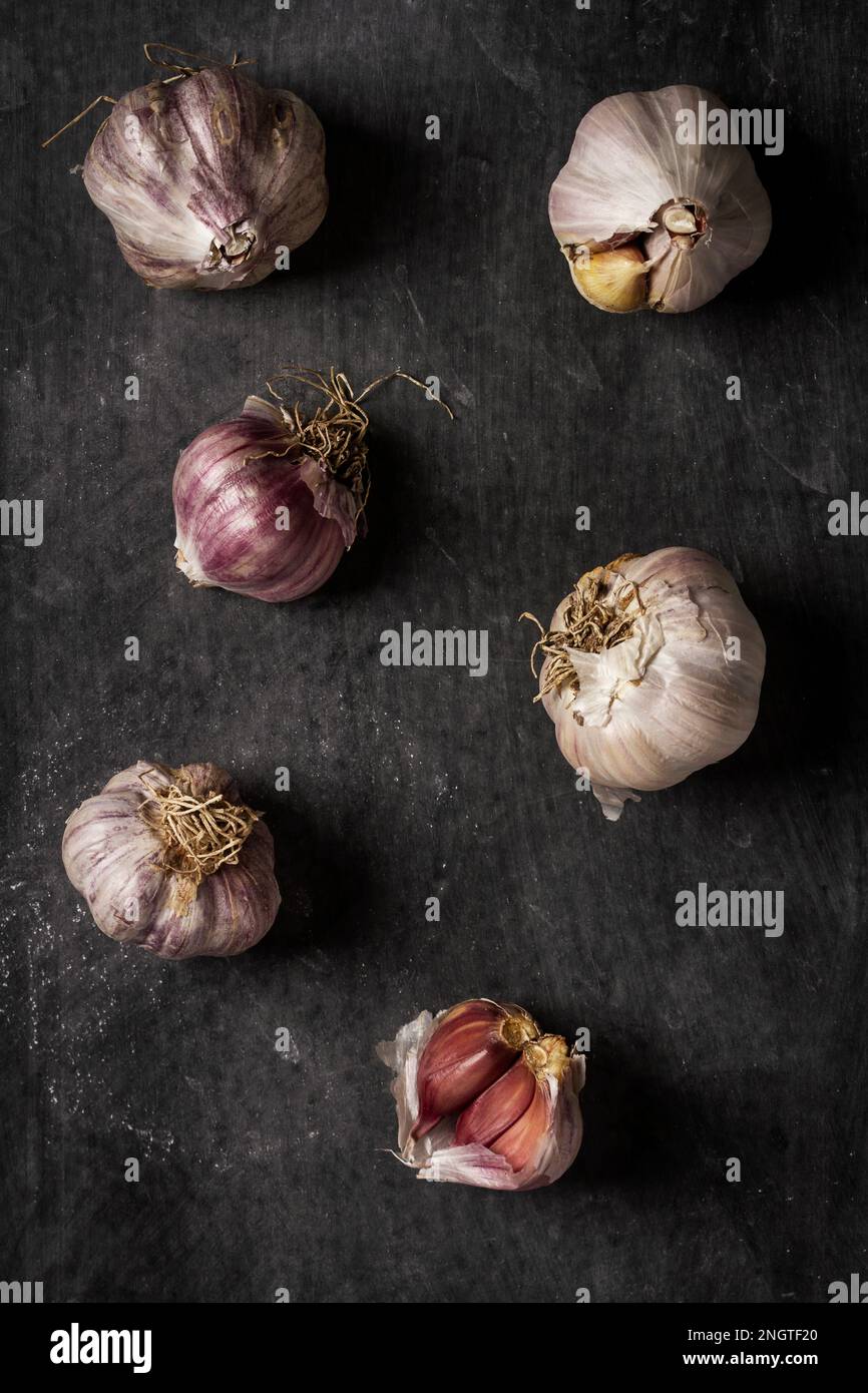 Fresh garlic bulbs and cloves grouped on black background. Flat lay ...