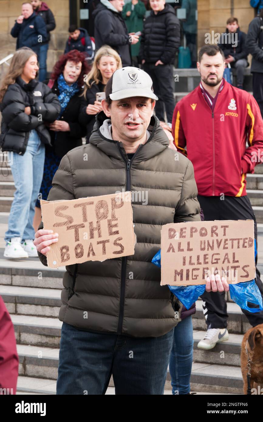 An anti-migrant demonstrator holds up stop the boats and deport migrants sign outside Lime Street station at the Refugees welcome rally iin Liverpool Stock Photo