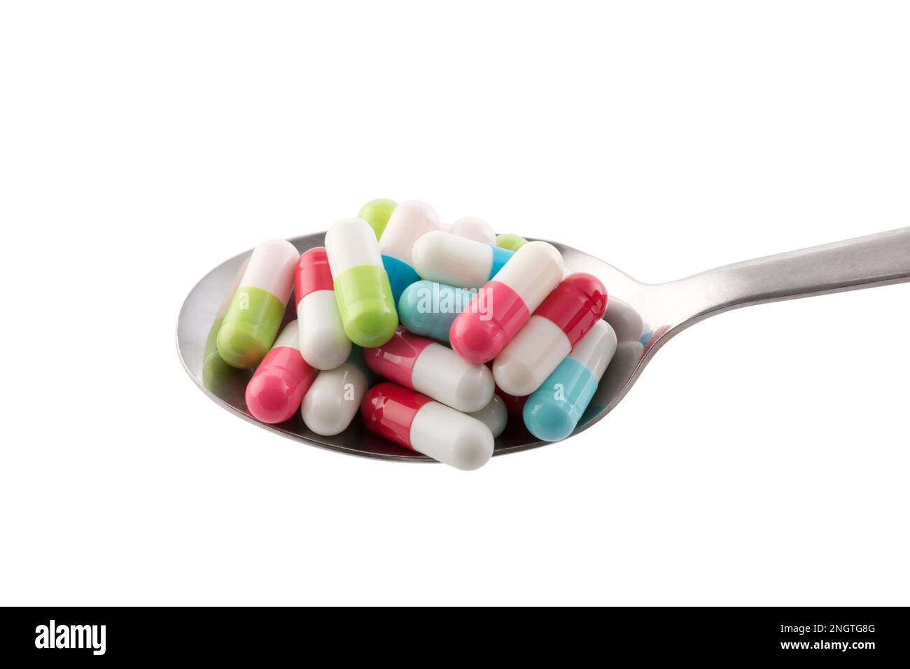 Colorful pills on spoon isolated on white background with clipping path Stock Photo