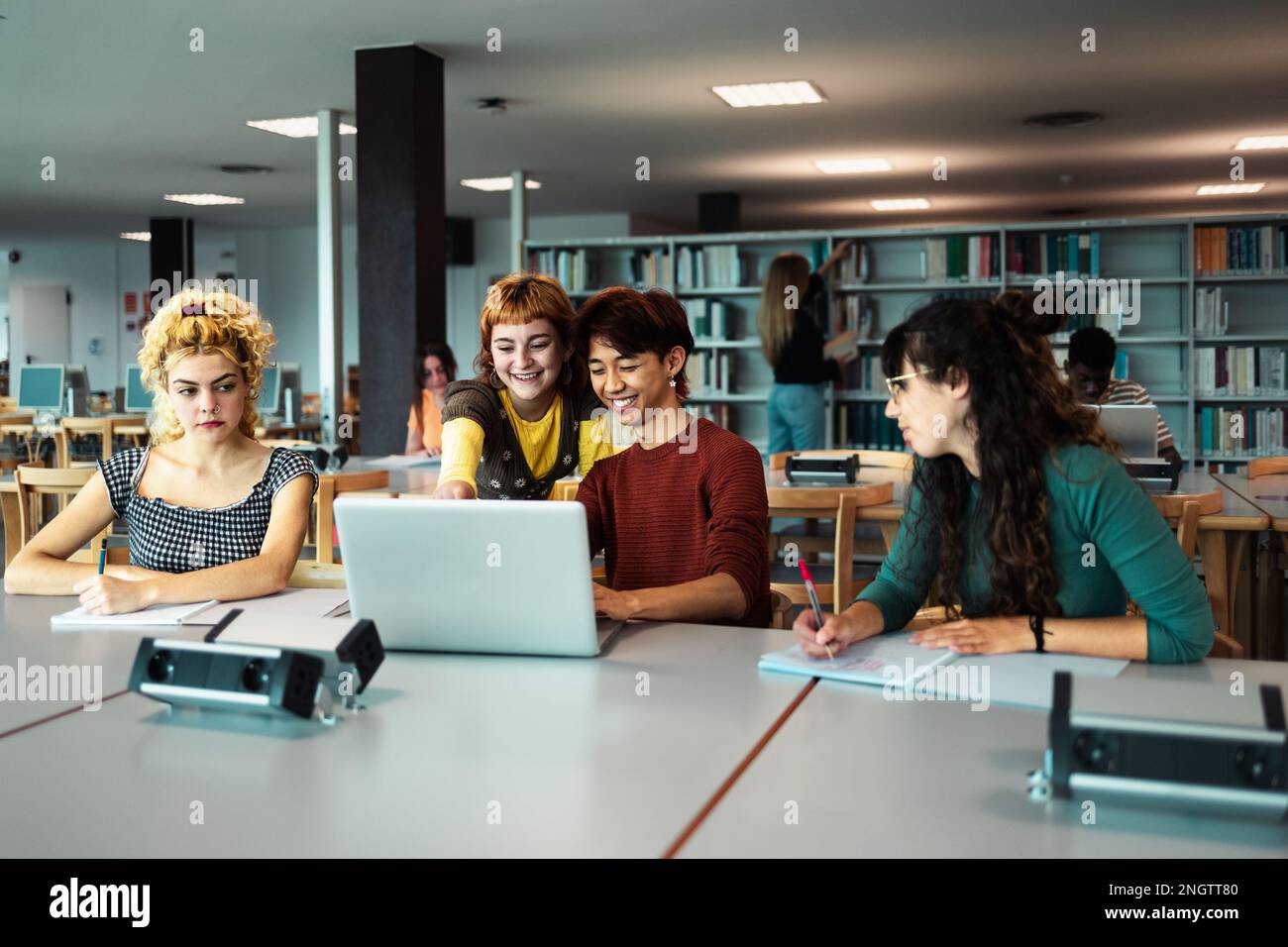 Young university students using laptop and studying with books in