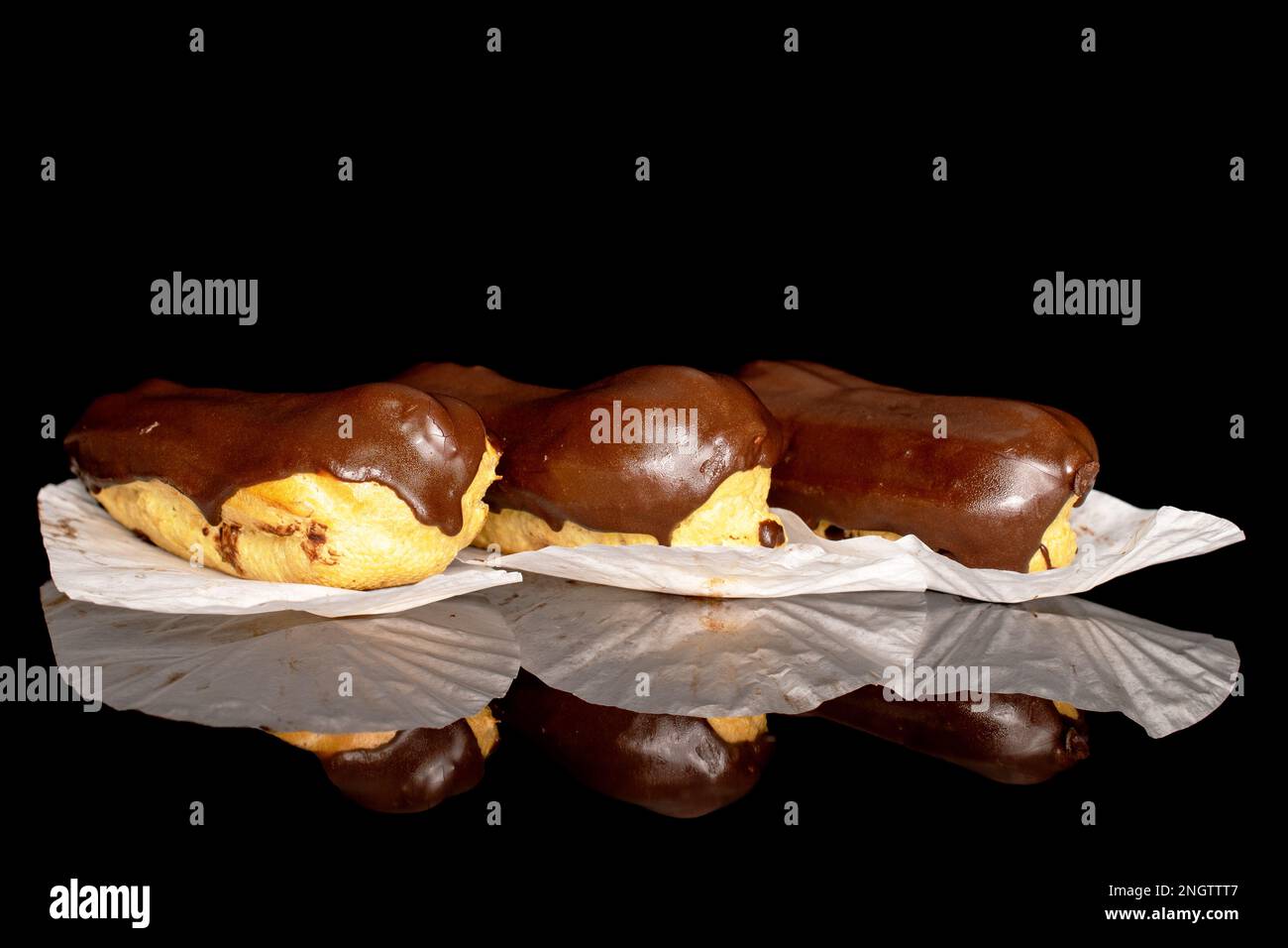 Three chocolate eclairs, macro, isolated on black background. Stock Photo
