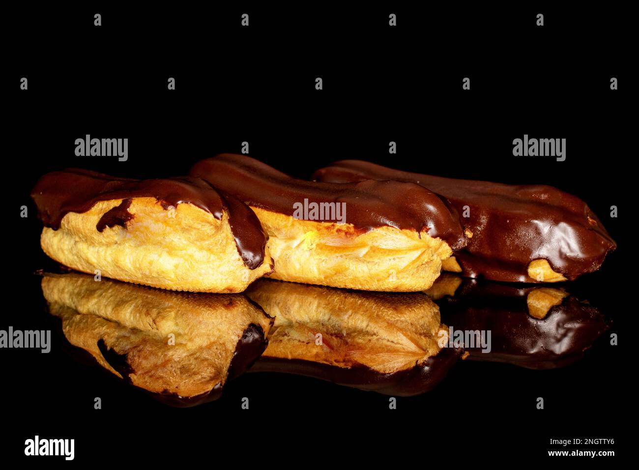 Three chocolate eclairs, macro, isolated on black background. Stock Photo