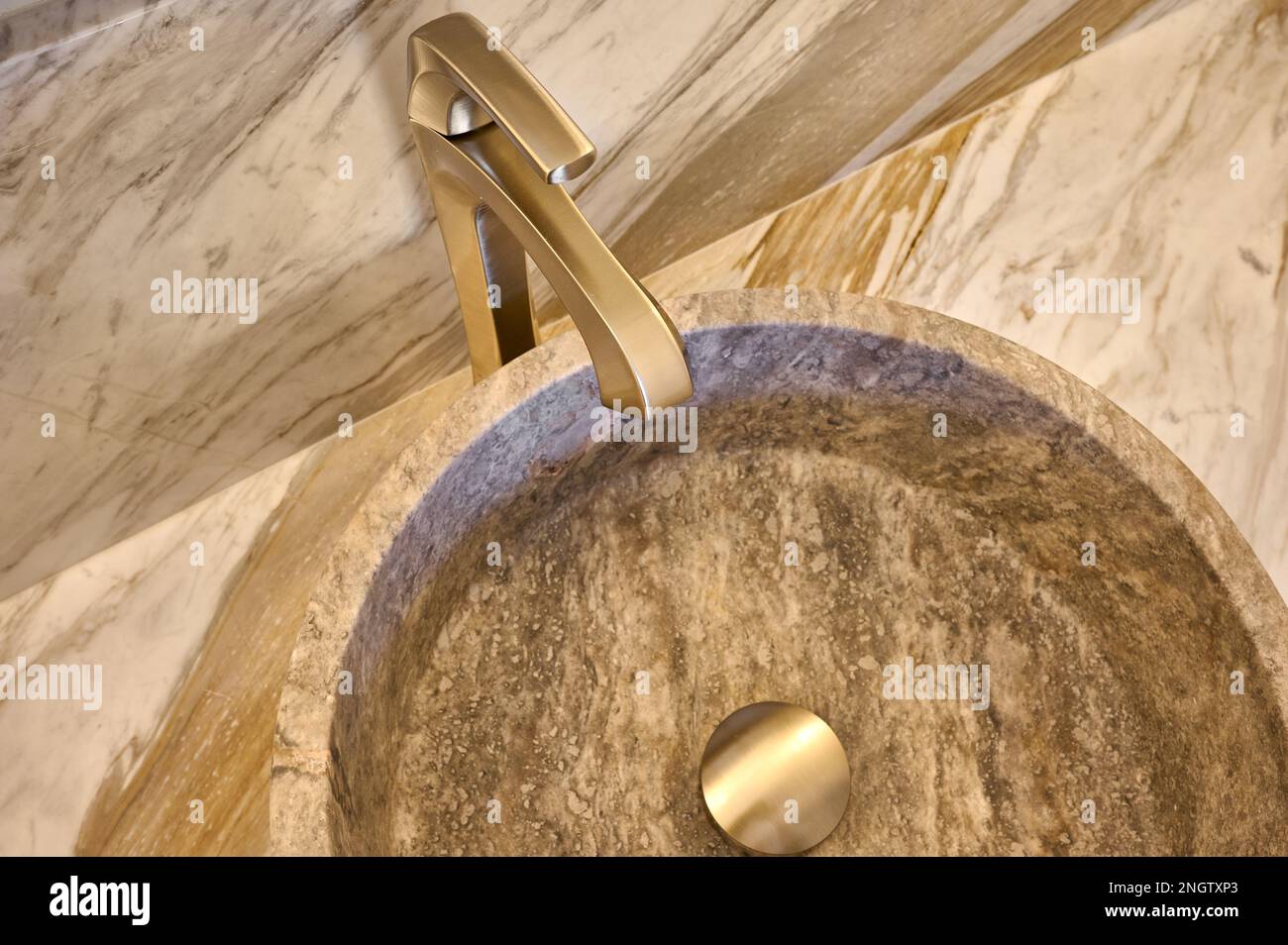 Closeup of Gold Faucet and round stone sink and countertop in bathroom Stock Photo