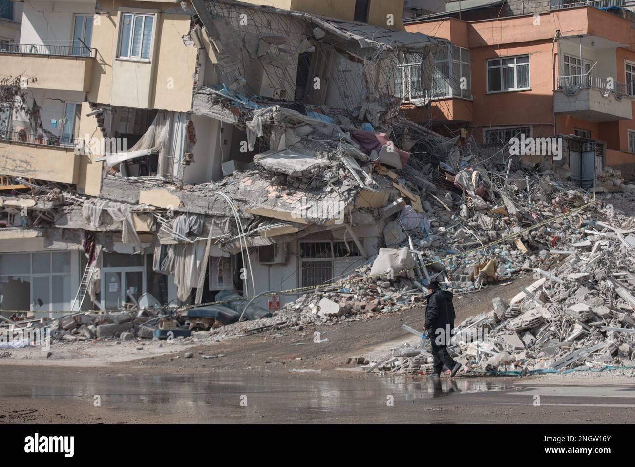 Kharamanmaras, Turkey. 18th Feb, 2023. A man walks past a collapsed