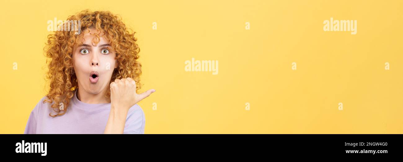 Woman with curly hair pointing surprised to the side Stock Photo