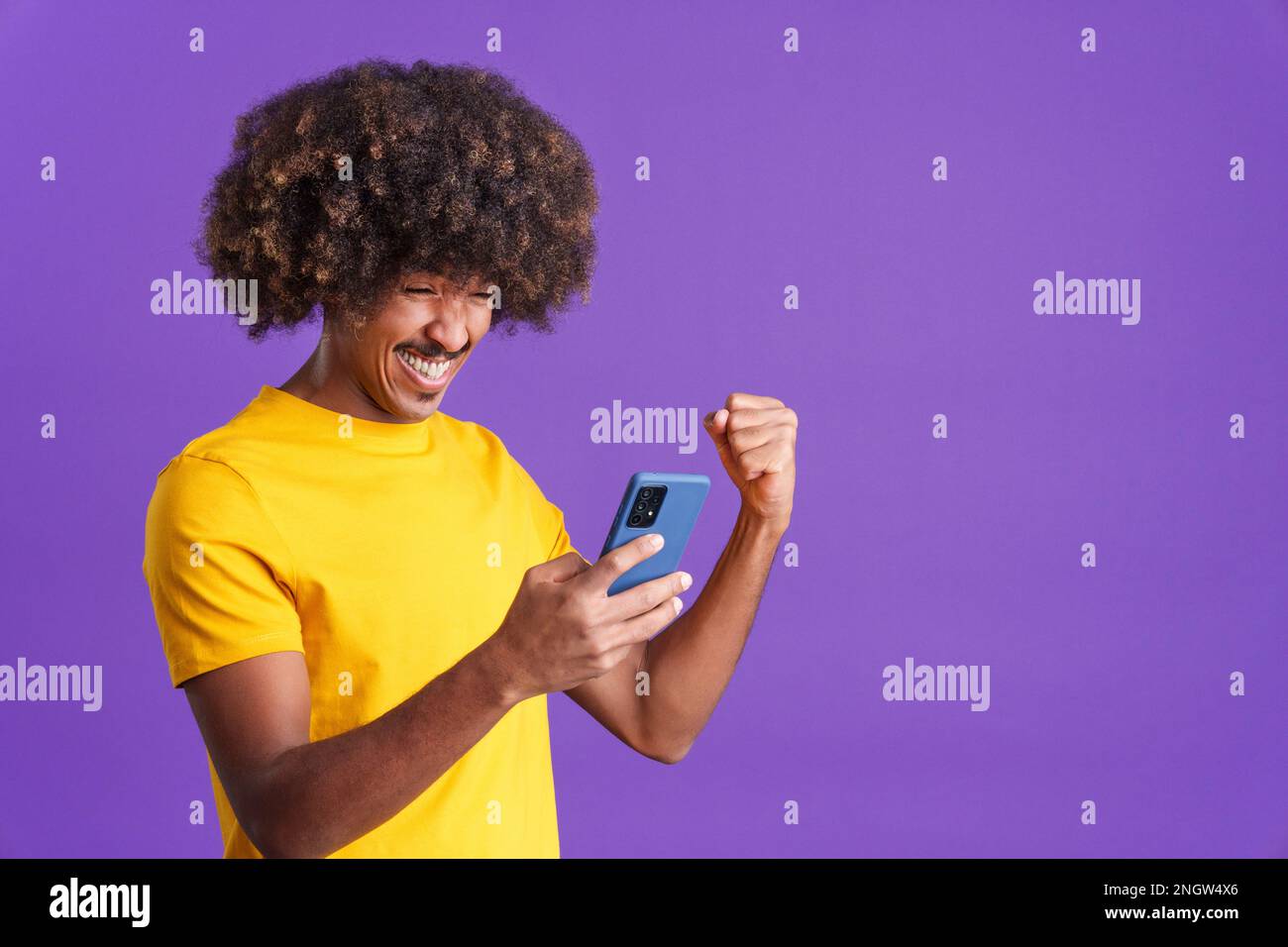 Excited african man celebrating while using the mobile phone Stock Photo