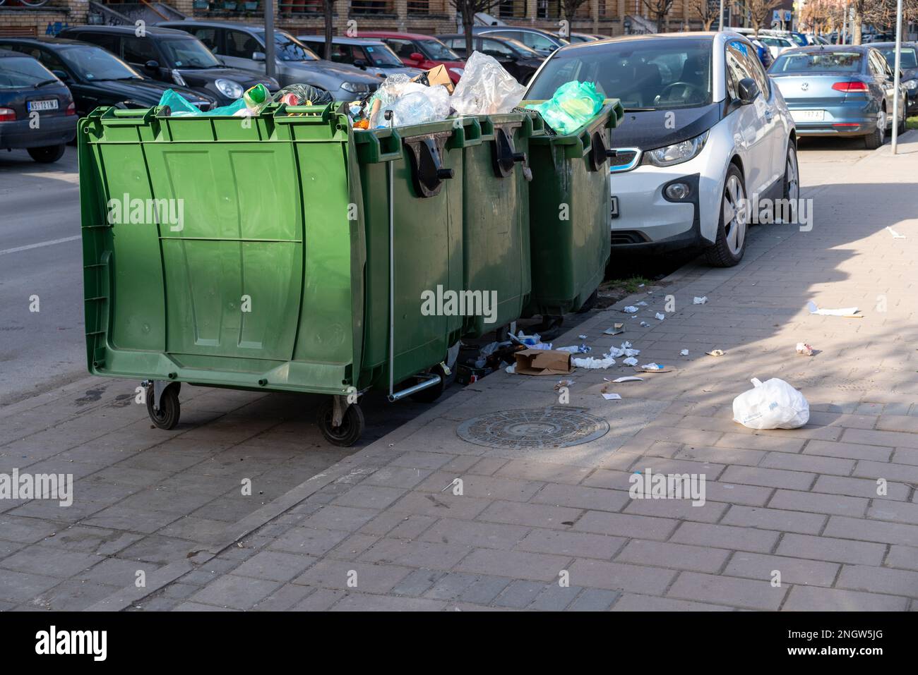 Overflowing trash cans on street in city. Problem rubbish disposal. Stock Photo
