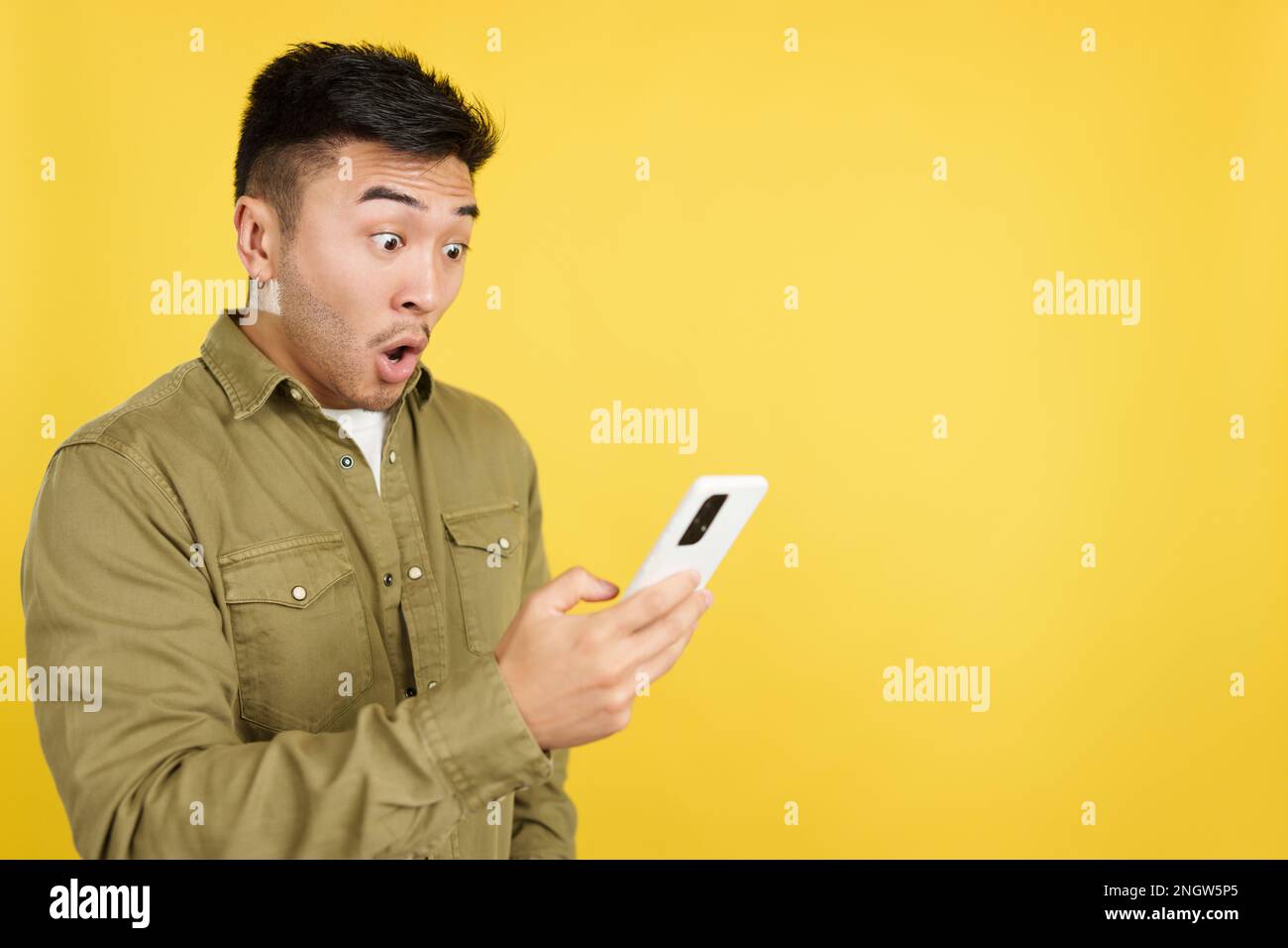 Surprised chinese man looking the screen of a mobile Stock Photo