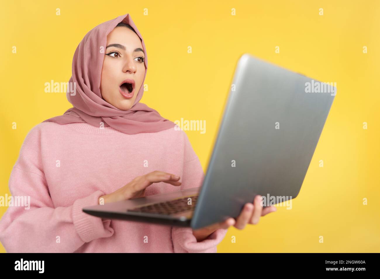 Surprised muslim woman with head scarf using a laptop Stock Photo - Alamy