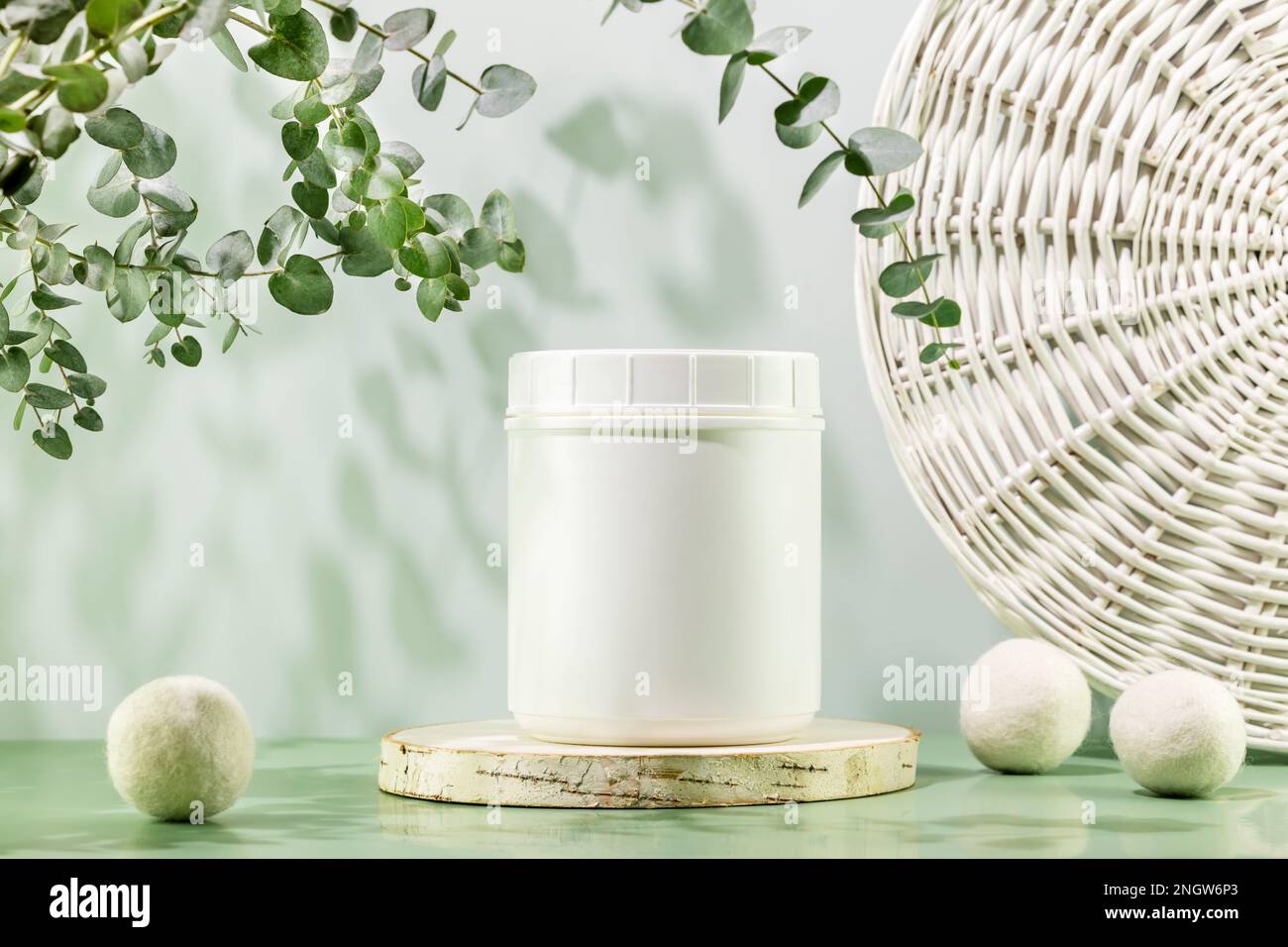 Natural laundry detergent mockup. Eco friendly washing concept with container of washing powder on wooden podium with laundry balls and eucalyptus spr Stock Photo