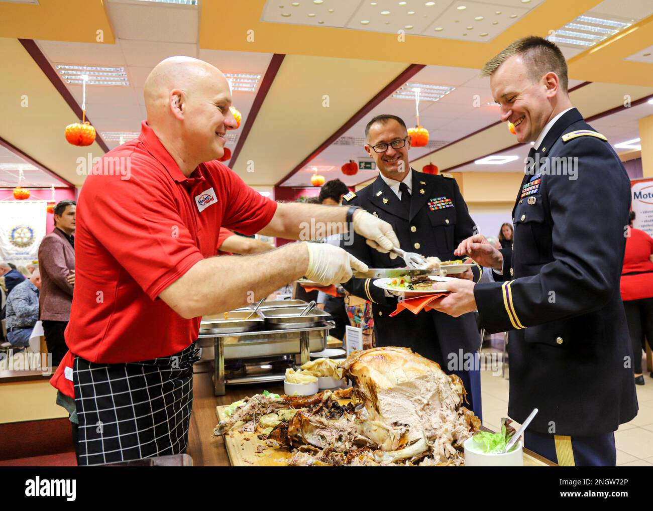 MARTIN, Slovakia - U.S. Army V Corps Maj. Steve Szrom, a Civil Affairs officer from Valparaiso, Indiana, holds up his plate to receive a slice of turkey as V Corps Capt. Robert Pavlovic, a Civil Affairs officer assigned to 418th Civil Affairs Battalion based out of Belton, Missouri, observes during Rotary International Club Martin’s Thanksgiving dinner, Martin, Slovakia, Nov. 24, 2022. Local community leaders representing the Rotary International Club invited U.S. Army V Corps Civil Affairs Soldiers from Camp Kosciuszko, Poland, to a Thanksgiving event to further promote, understand and celebr Stock Photo