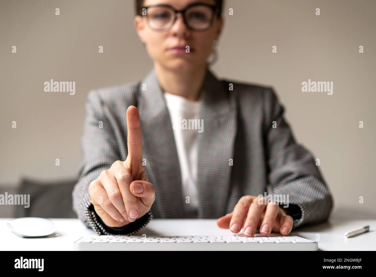 Businesswoman with glasses sitting desk working on computer touching blank virtual screen, space for insert infographic. Stock Photo