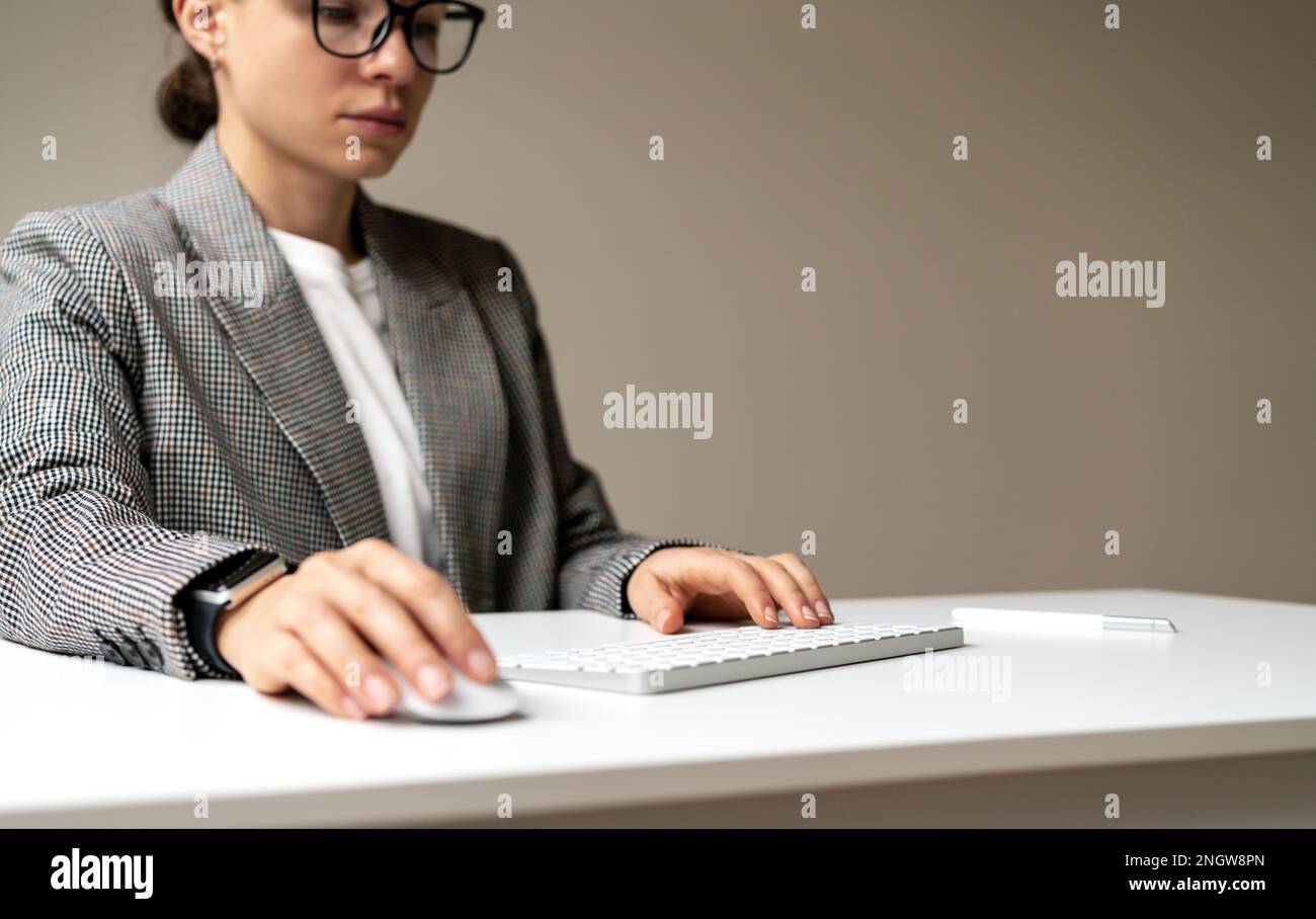 Businesswoman working on pc with blank virtual monitor using wireless keyboard and computer mouse, space for photomontage insert infographic. Stock Photo