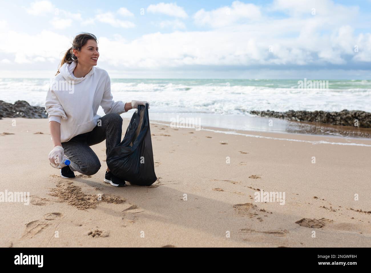 Ocean's pollutions. Young female volunteer putting plastic bottles in