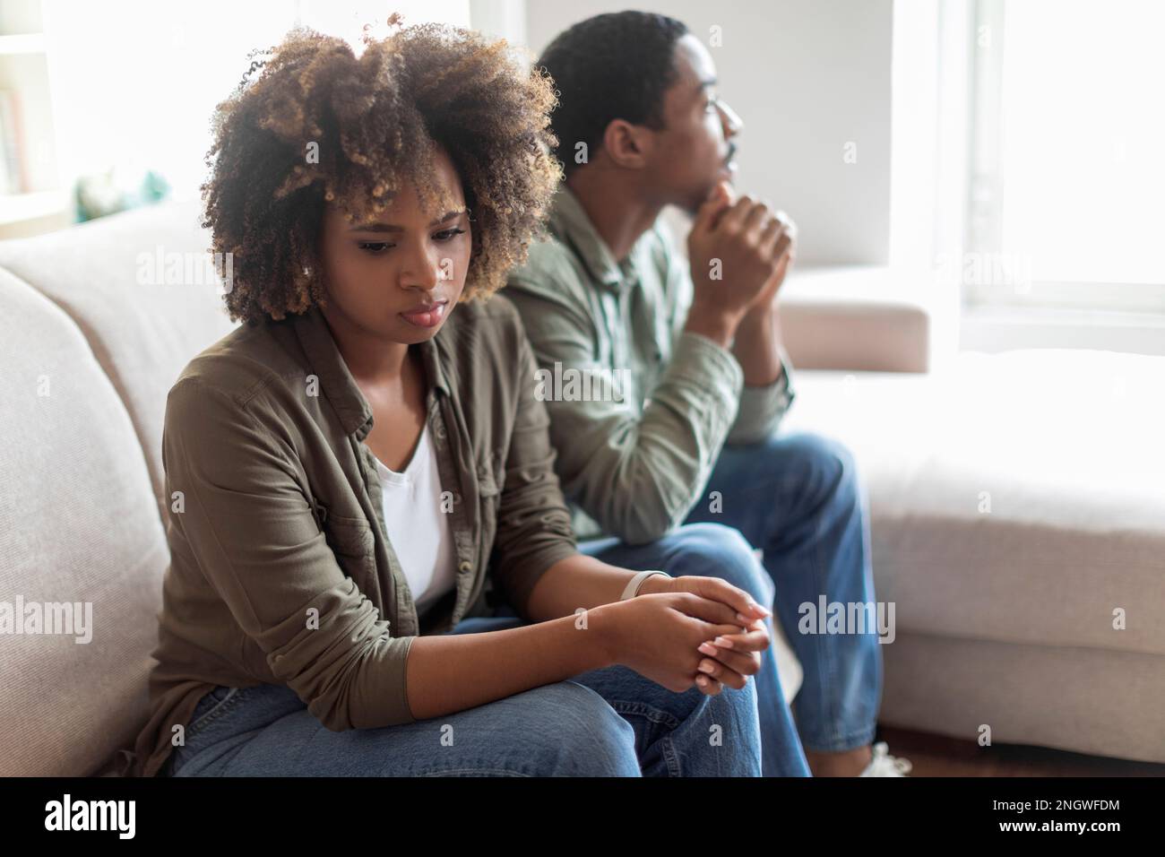 Sad african american couple sit on couch back to back Stock Photo - Alamy
