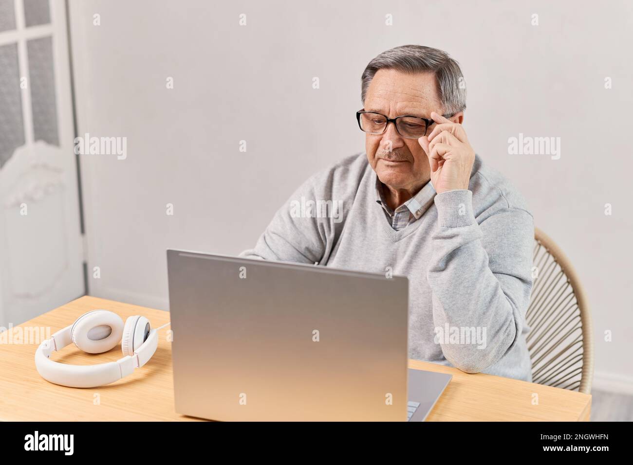 Senior man at home connected on laptop computer Stock Photo