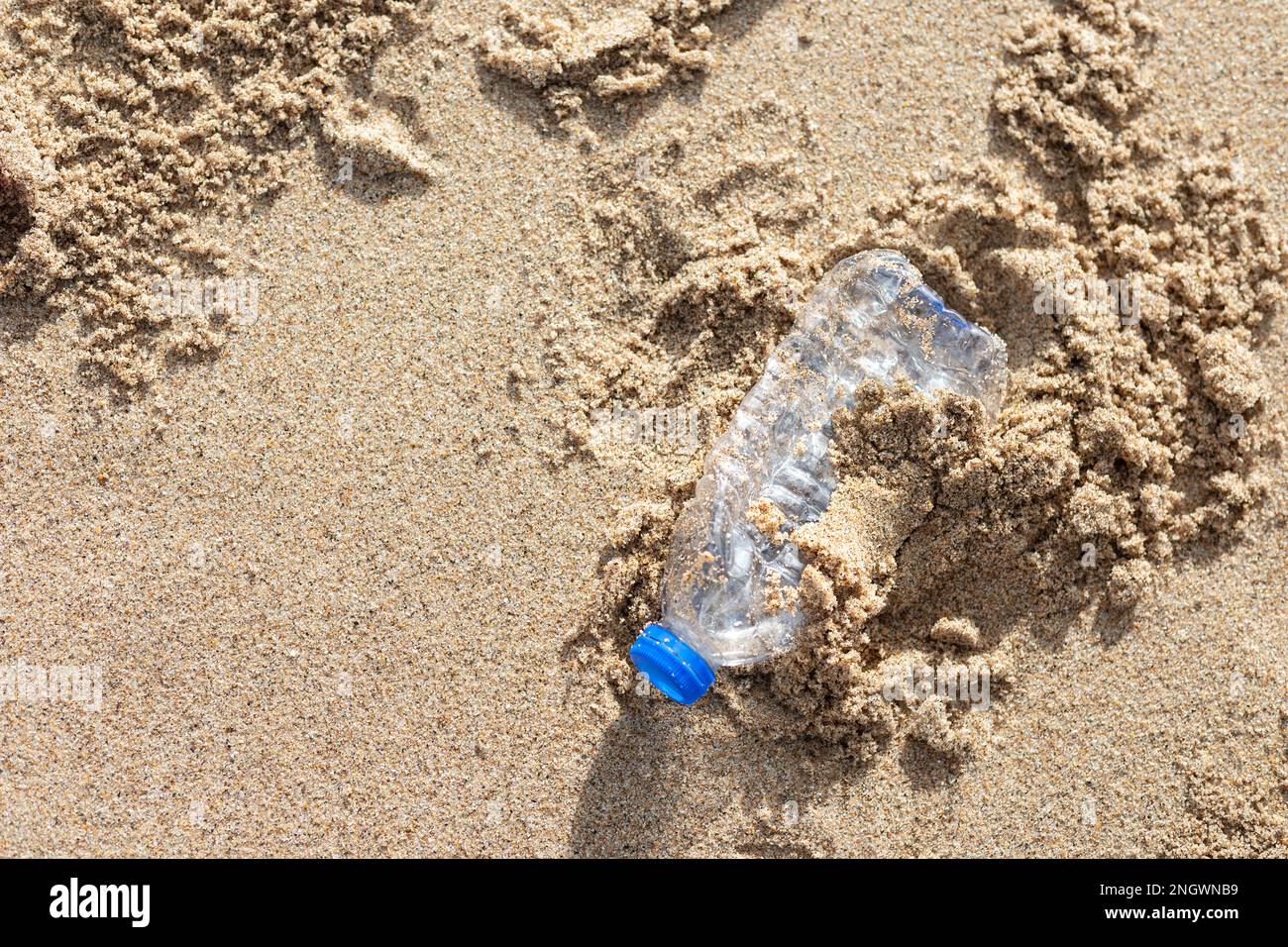 Environmental pollution. Human waste throwing away junk bottle on the sand, bring the sea to rot