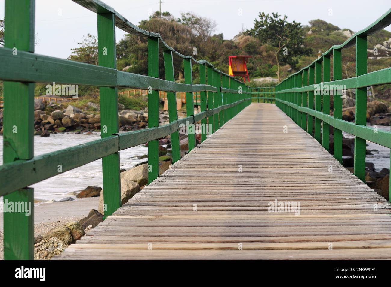 footbridge that joins the beach community to a small island. Construction made of wood, painted green. Stock Photo