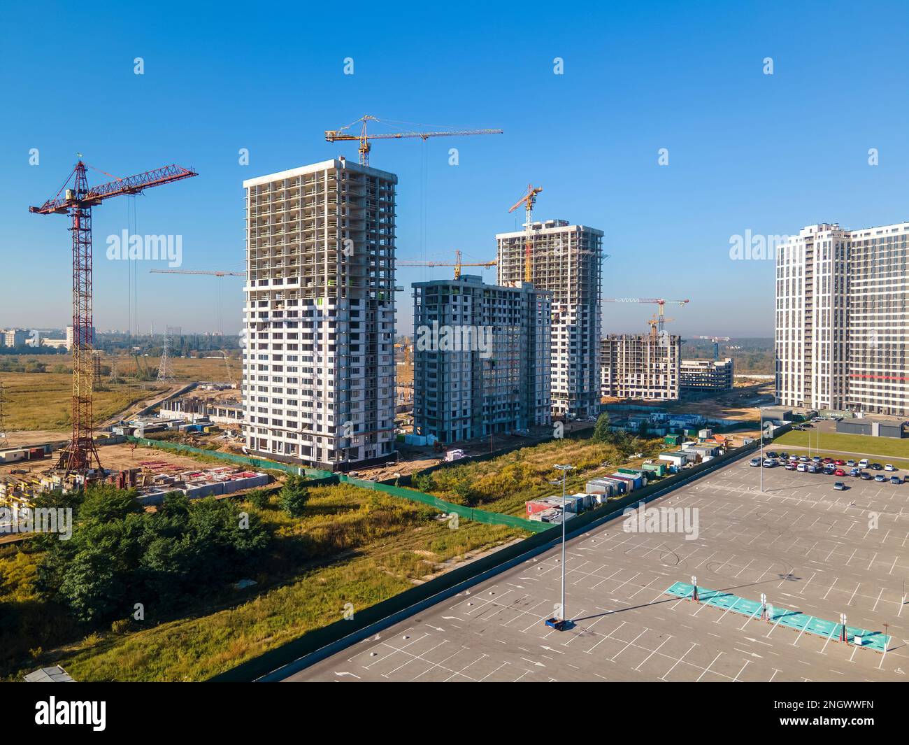Parking lot and construction site with cranes in a bright sunny day. New real estate development Stock Photo