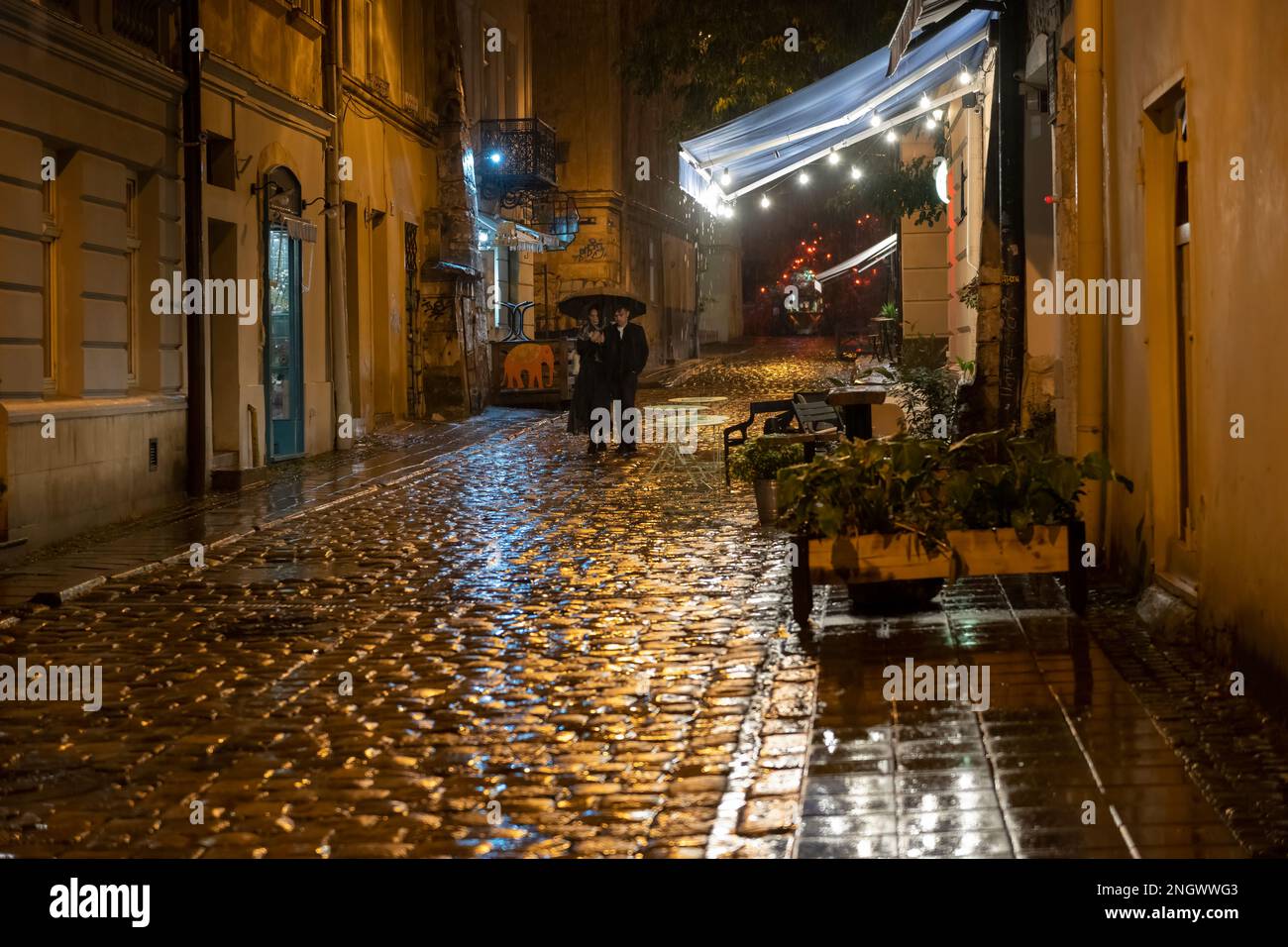 2020-09-29 Lviv, Ukraine. Rainy night on the old lviv city streets. A pair with umbrella goes under the pouring rain Stock Photo