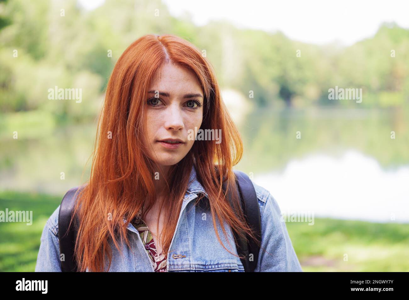 authentic young woman wearing denim jacket and backpack outdoors on a
