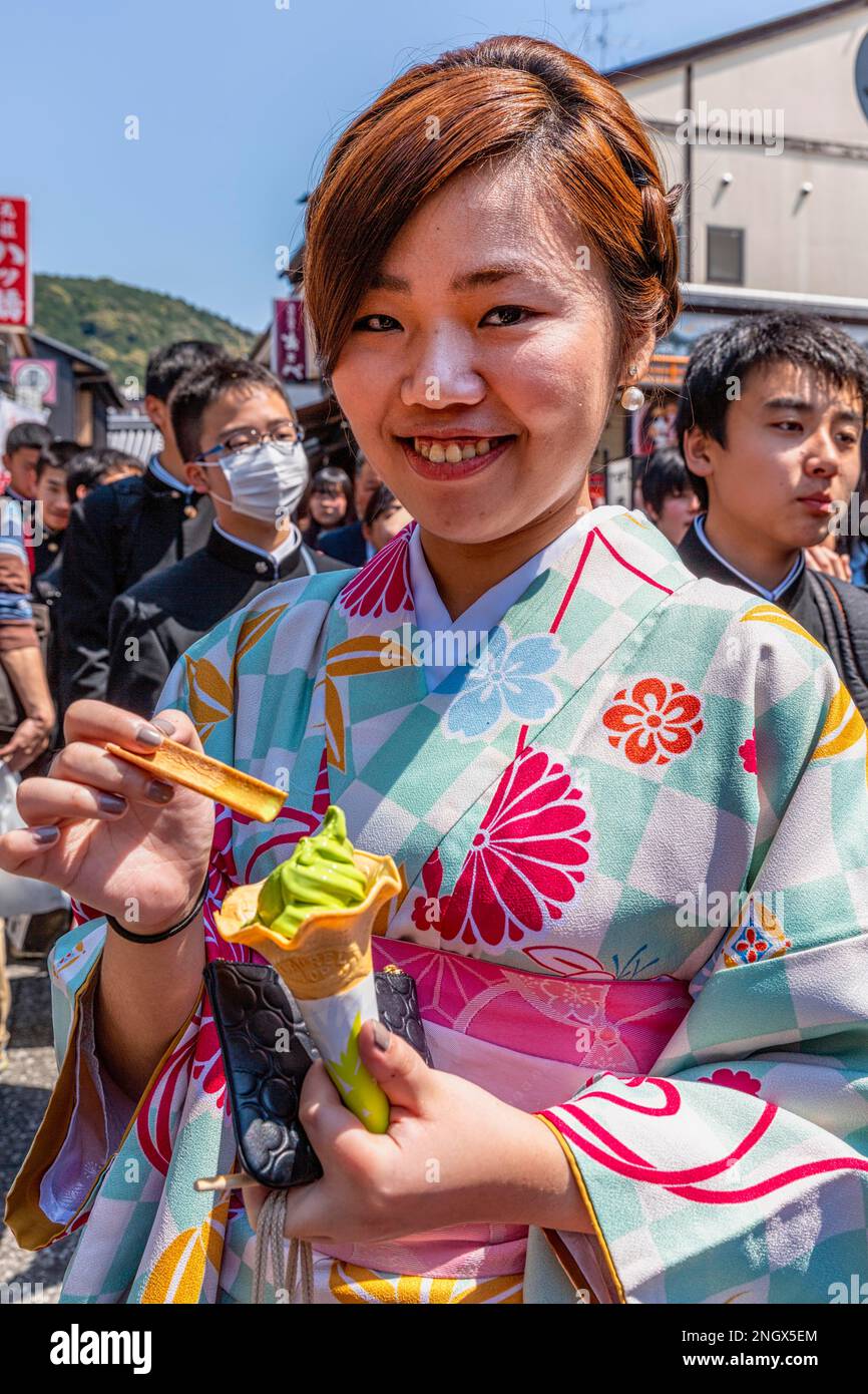 Kyoto Japan. Smiling woman wearing traditional kimono, eating an ice