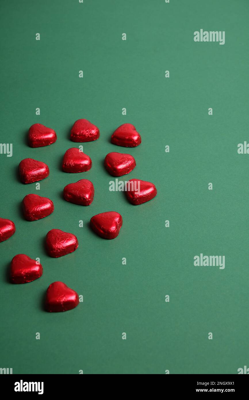 photo of red hearts lying on a green uniform background Stock Photo