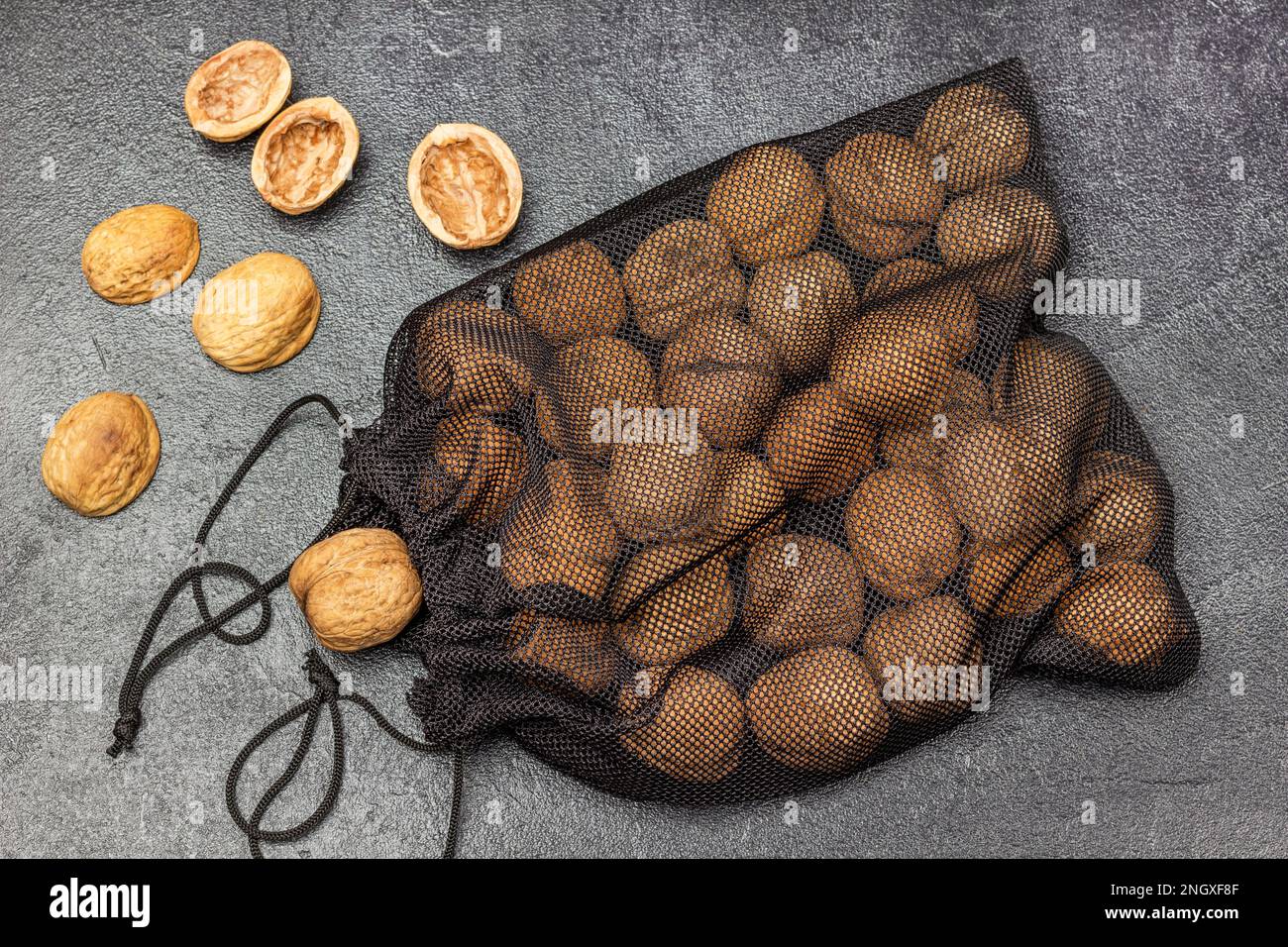 Whole walnuts in a black mesh resealable bag. Nut shell on the table