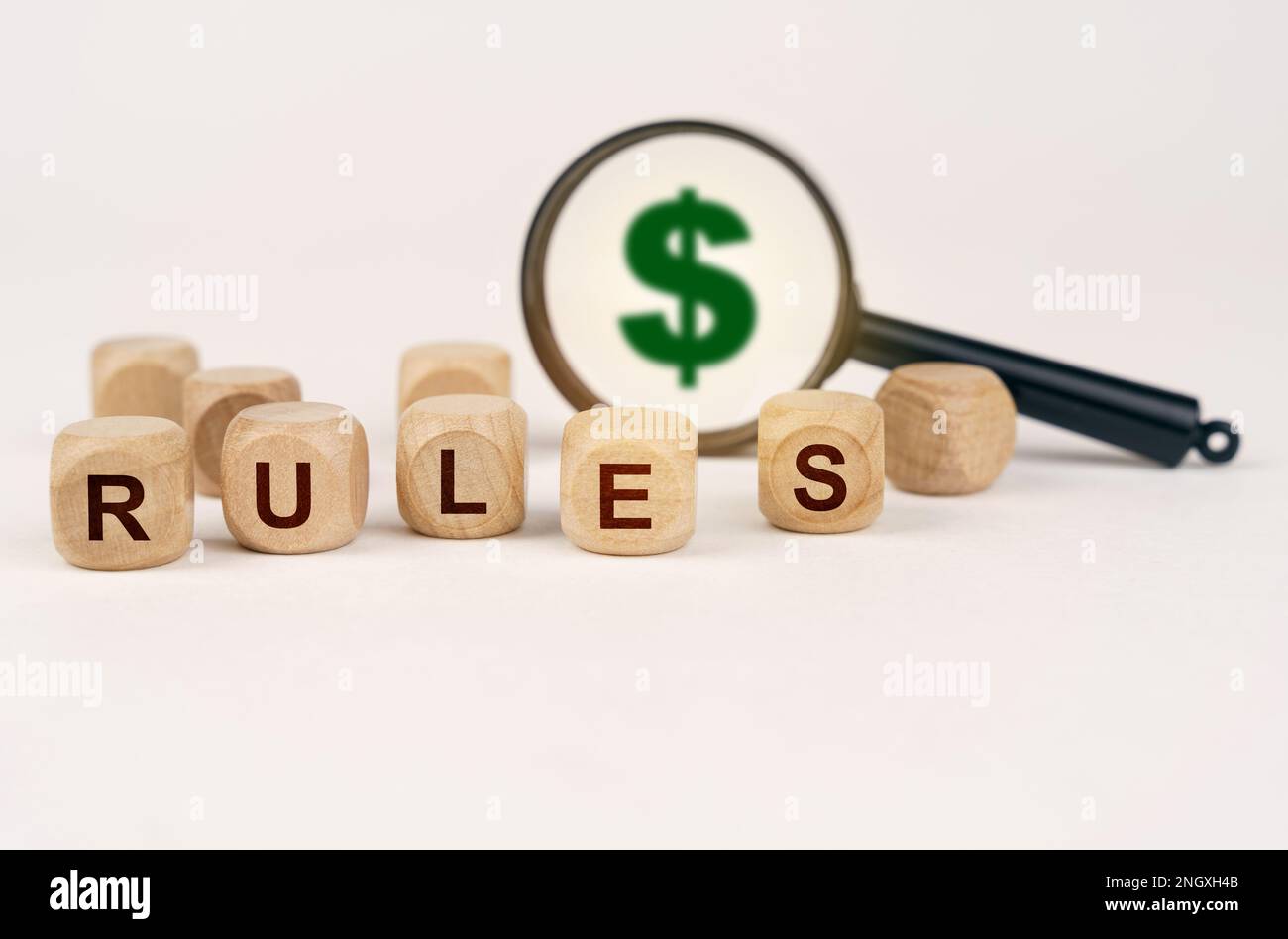 Business concept. On a white surface, a magnifying glass with a dollar symbol and cubes with the inscription - RULES Stock Photo