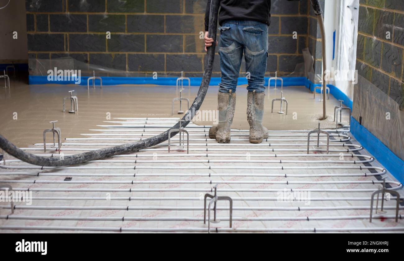 Floor screed being poured out over underfloor heating pipes Stock Photo