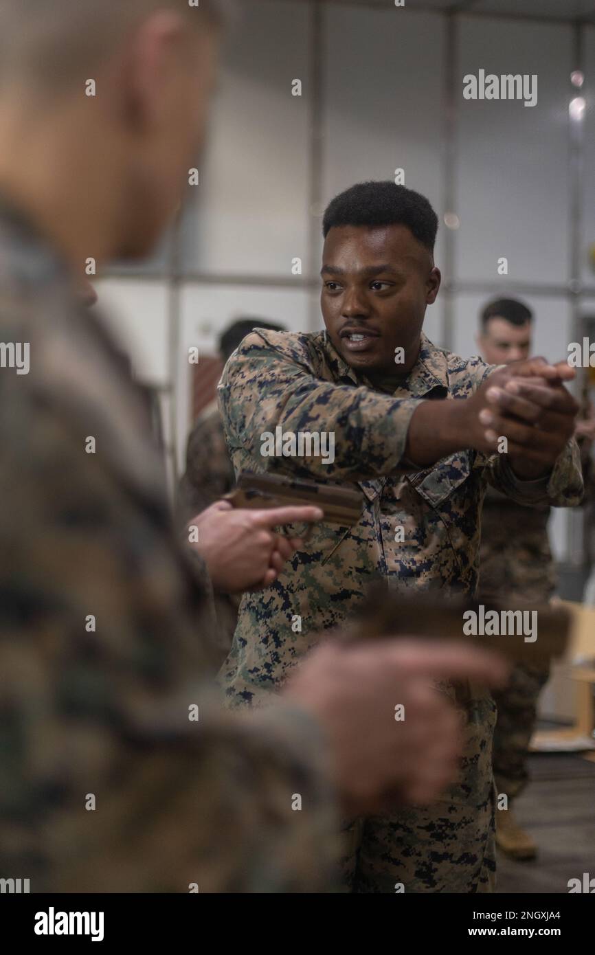 U.S. Marine Corps Cpl. Justin McDonald, a bulk fuel specialist, assigned to 8th Engineer Support Battalion, 2nd Marine Logistics Group, II Marine Expeditionary Force (MEF) and native of Blytheville, Arkansas, instructs Marines on firing positioning during an M18 weapons familiarization course aboard the Spearhead-class expeditionary fast transport USNS Trenton (T-EPF 5), November 30, 2022. Marines assigned to II MEF, based out of Camp Lejeune, North Carolina, embarked aboard USNS Trenton (T-EPF 5) to improve interoperability while refining the U.S. capability to rapidly deploy forces aboard U. Stock Photo