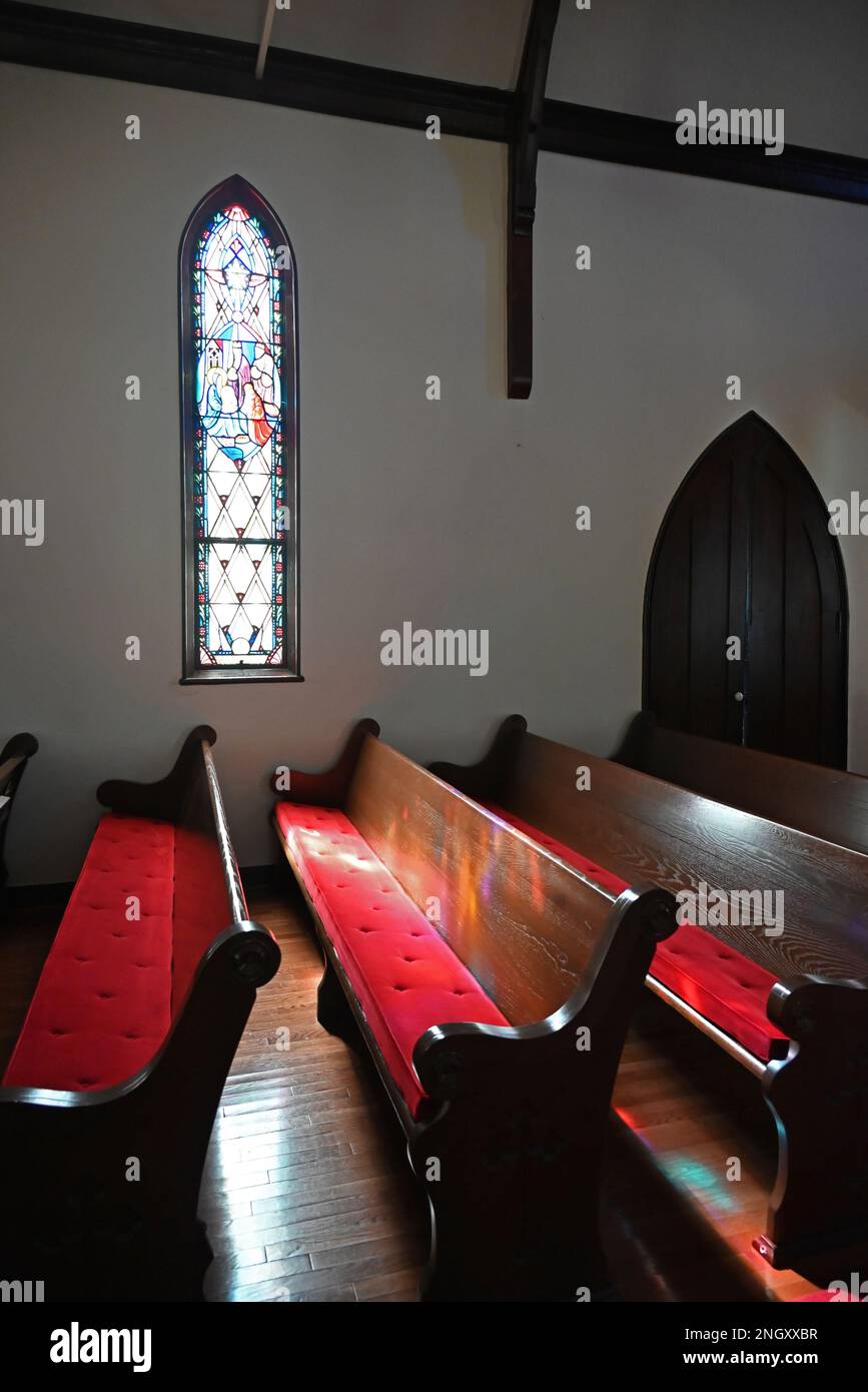 Sunlight streams through stain glass windows onto pews at the holy