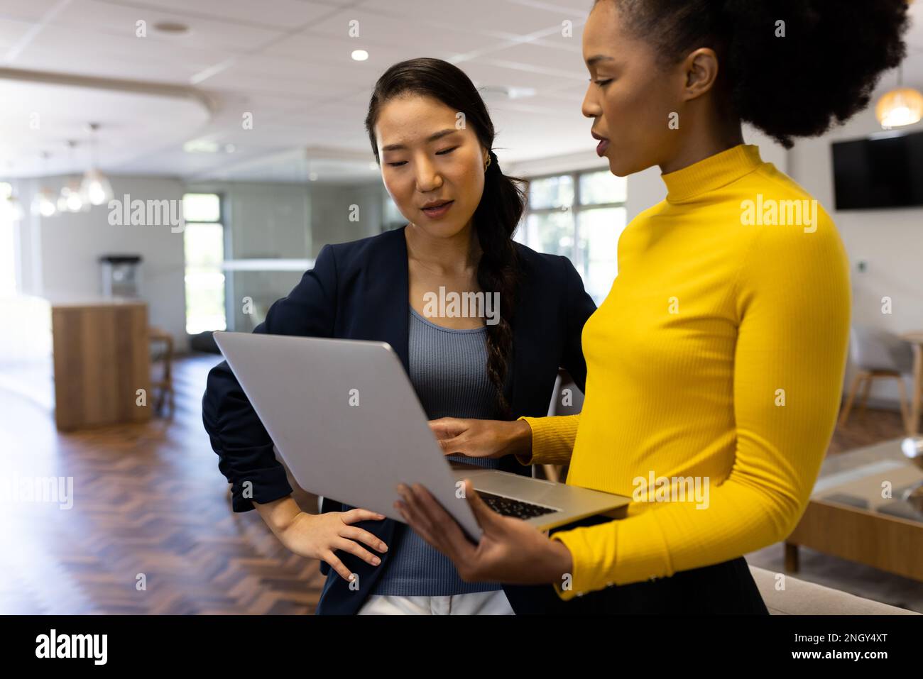 Diverse businesswomen with laptop working and talking in office Stock ...