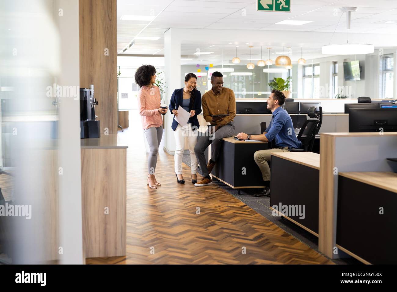 Diverse businesspeople in office talking and laughing Stock Photo