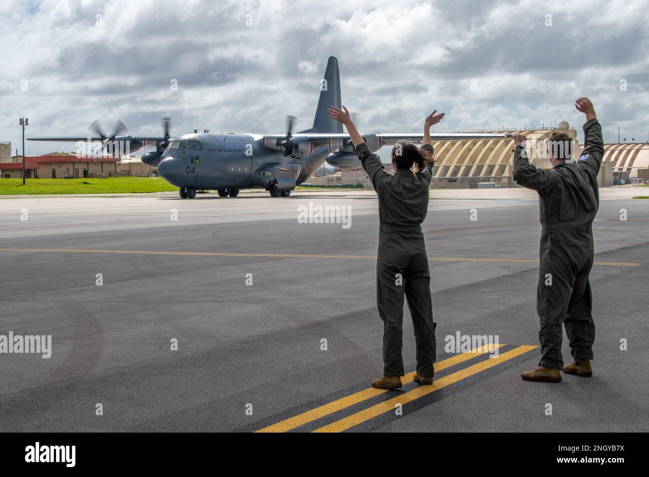 (Left to right) U.S. Air Force Capt. Jenn Brenton, and Capt. Andrew Zaldivar, 36th Expeditionary Airlift Squadron, greet a Royal New Zealand Air Force C-130H Hercules at Andersen Air Force Base, Guam, Dec. 1, 2022, during Operation Christmas Drop 2022. Operation Christmas Drop is the longest-running Department of Defense humanitarian mission that delivers critical aid to island communities throughout the western Pacific while also providing an opportunity for aircrew to hone important skills needed for future operations. Stock Photo