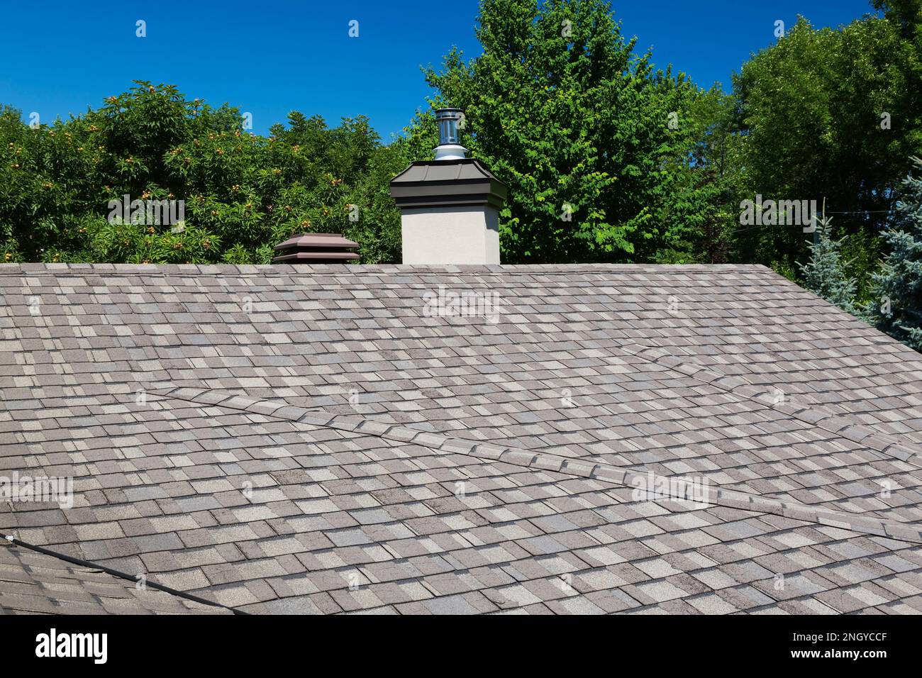 Grey and tan nuanced asphalt shingles roof on luxurious house in summer. Stock Photo