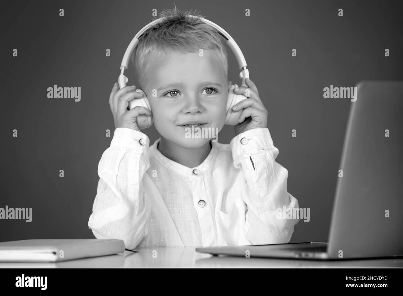 Clever school boy, cute pupil wears headphones writing on laptop ...