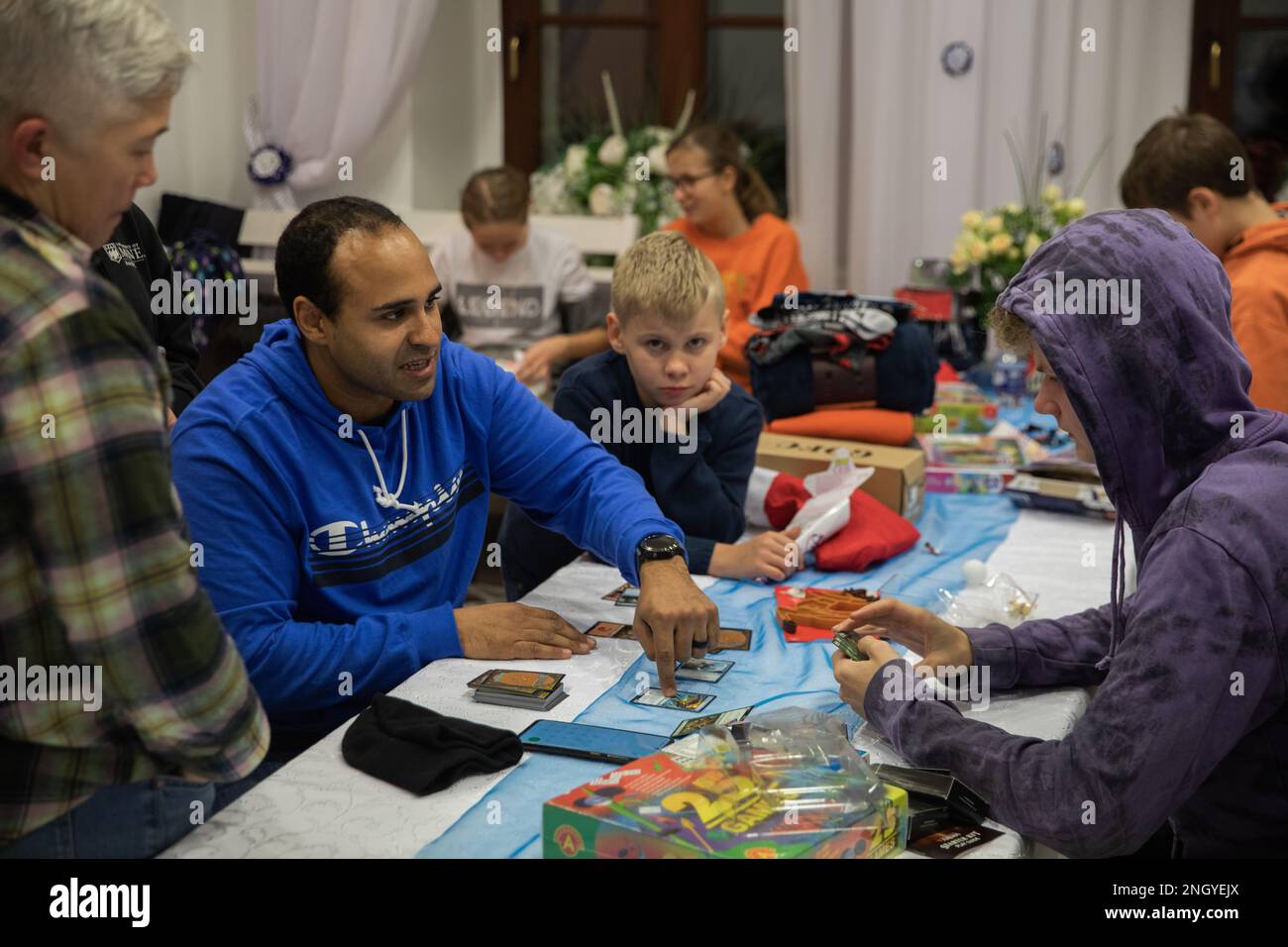 U.S. Army Cpl. Bennie Long, a battalion religious affairs noncommissioned officer with the 1st Infantry Division (1 ID)  , teaches children how to play a card game after a gift exchange in Bolesławiec, Poland, Dec. 1, 2022. The gifts were donated to children living at the Dom Dziecka P.W. Sw. Jozefa Zgromadzenia Sióstr Elżbietanek, the Orphanage of St. Joseph of the Congregation of the Elizabethan Sister, by Soldiers assigned to the 1 ID who are working in communities of NATO allies and regional security partners while providing combat-credible forces to V Corps, America’s forward deployed cor Stock Photo