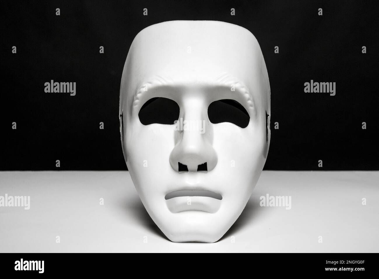 An expressionless mask of white color on a smooth white surface and ...