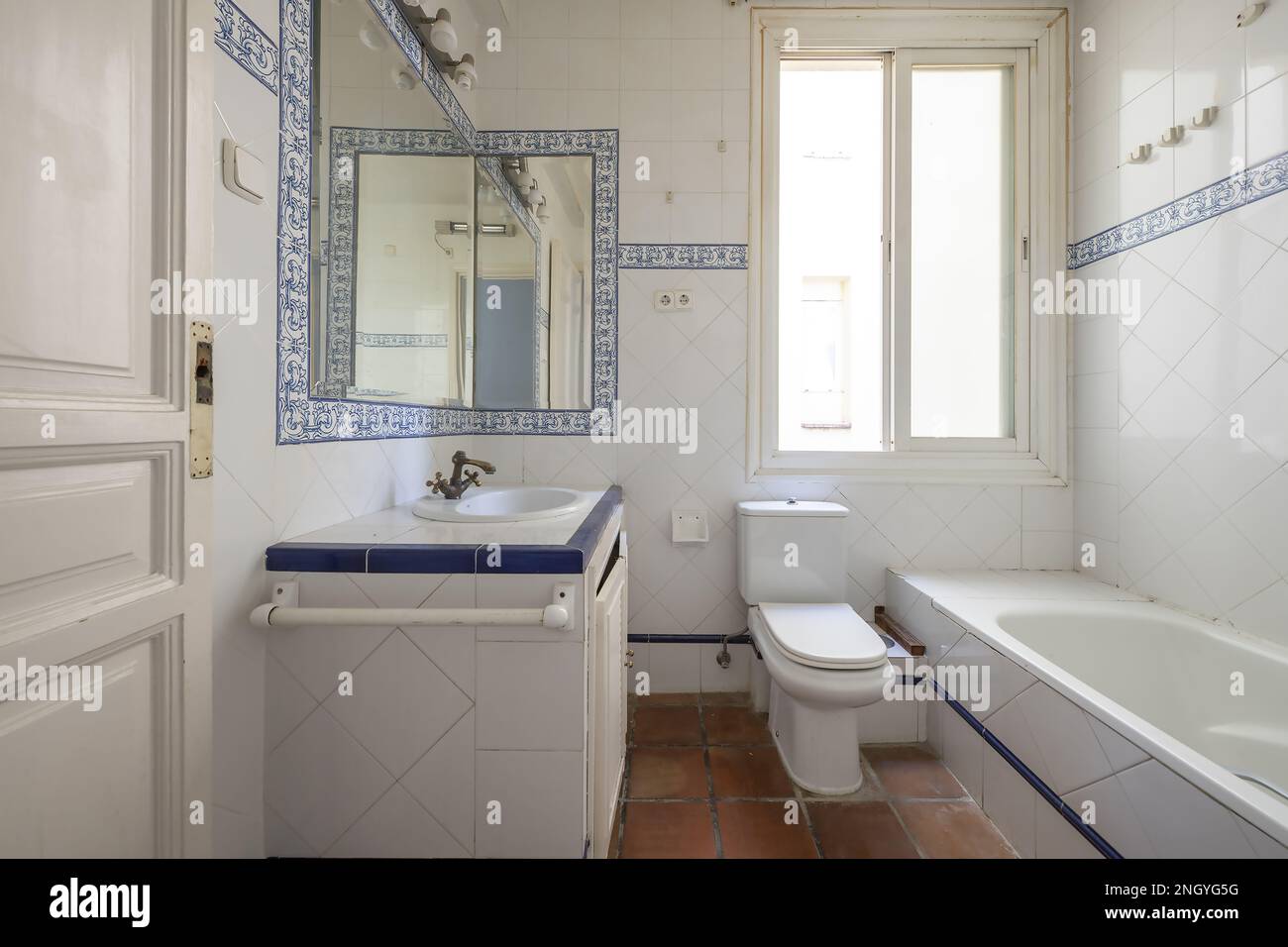 Bathroom with vintage style white tiles with blue borders and blue patterned borders Stock Photo