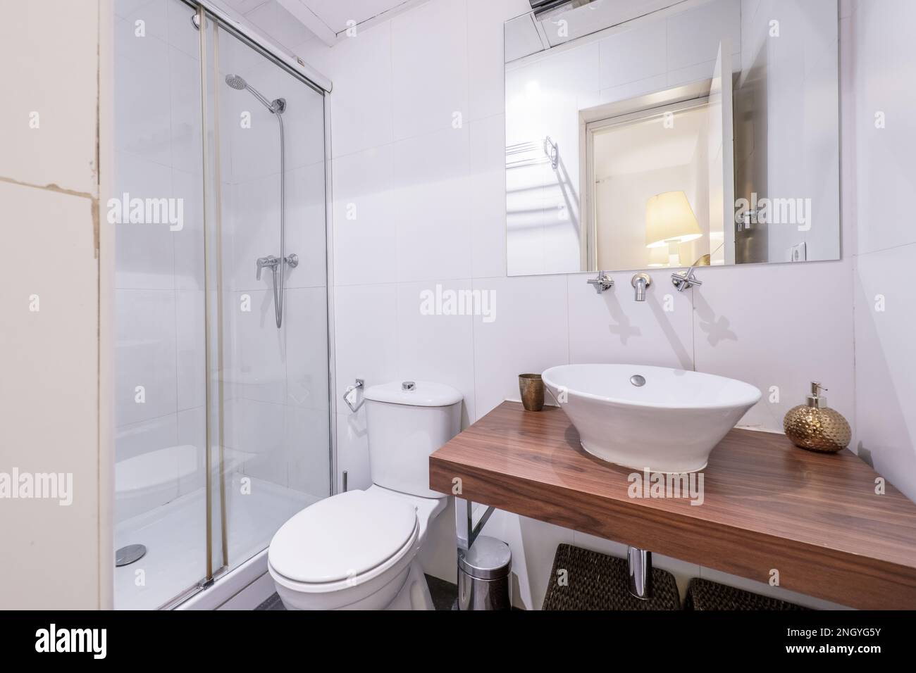 Small bathroom with porcelain sink on dark wood paneling and mirrors