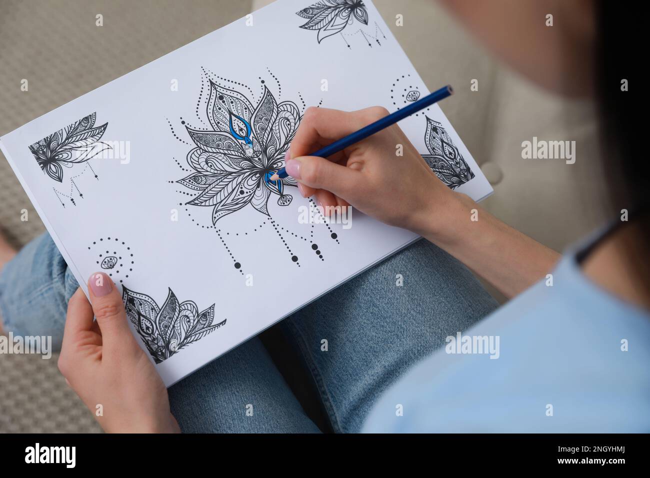 Young woman coloring antistress page on sofa, closeup Stock Photo