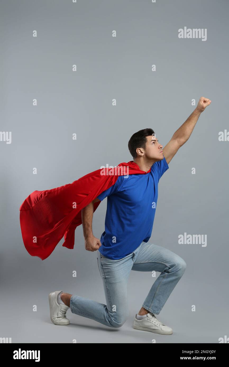 Man wearing superhero cape on grey background Stock Photo - Alamy
