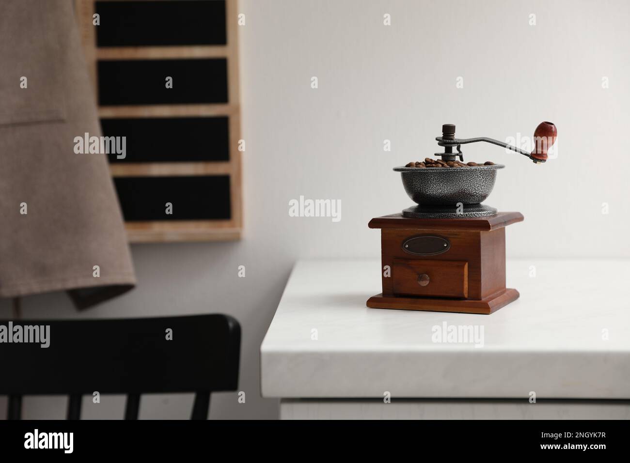 Vintage manual coffee grinder with beans on counter in kitchen Stock