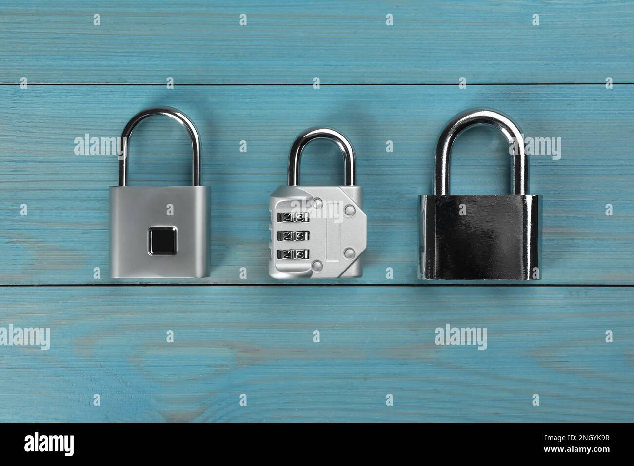 Different padlocks on light blue wooden table, flat lay Stock Photo