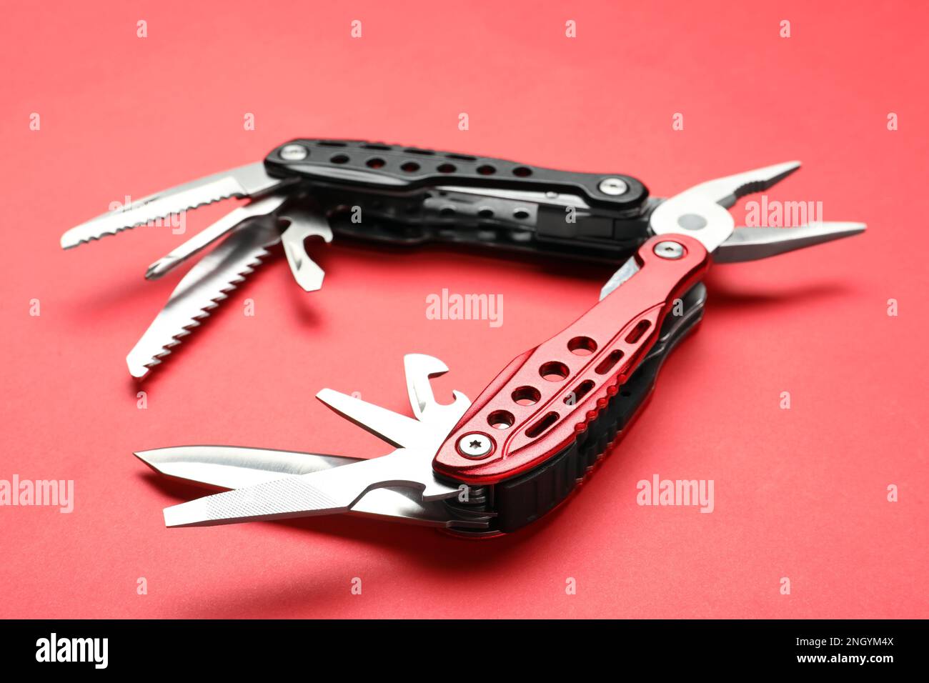 Compact portable multitool on red background, closeup Stock Photo