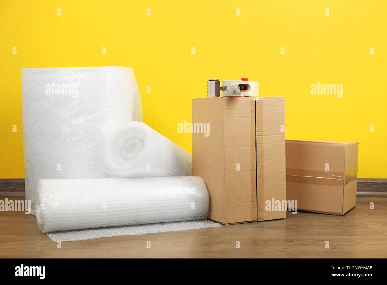 Bubble wrap rolls, tape dispenser and cardboard boxes on floor near