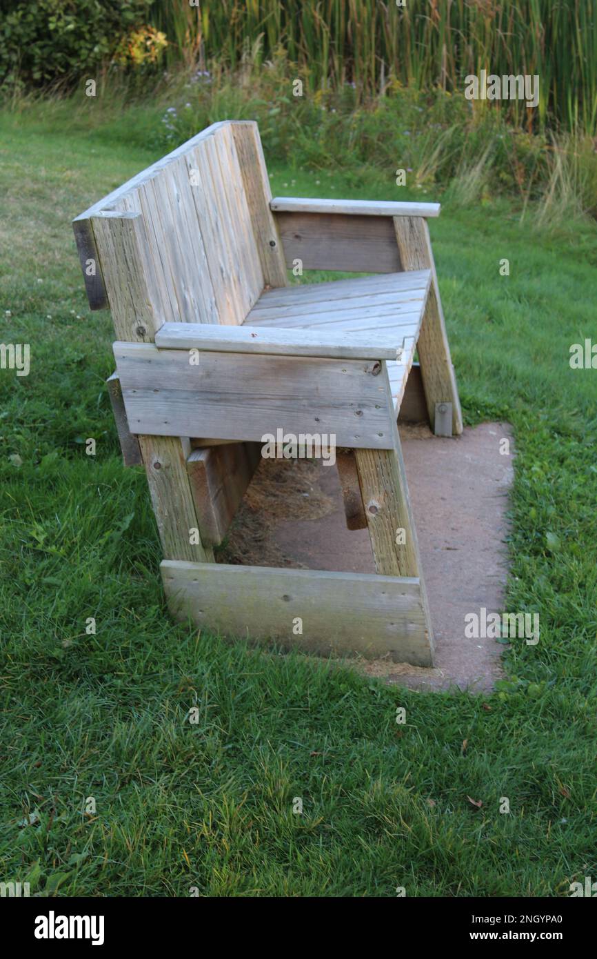 Isolated plain beige wooden bench with no one on it in grass at dusk Stock Photo