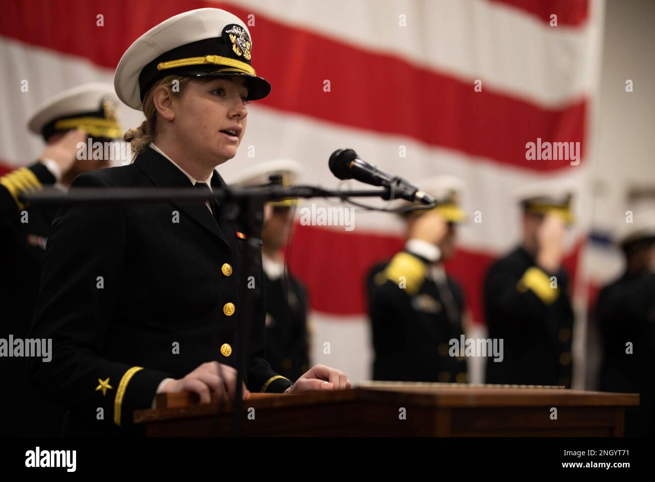 221202-N-LZ839-1139  NORFOLK, Va. (Dec. 2, 2022)  Ensign Mackenzie Hirth, a Deck department divisional officer assigned to the Wasp-class amphibious assault ship USS Bataan (LHD 5), sings the national anthem during the ship’s change of command ceremony in the hangar bay, Dec. 2, 2022. During the ceremony, Capt. Paul Burkhart relieved Capt. Joseph Murphy as commanding officer of Bataan. Stock Photo