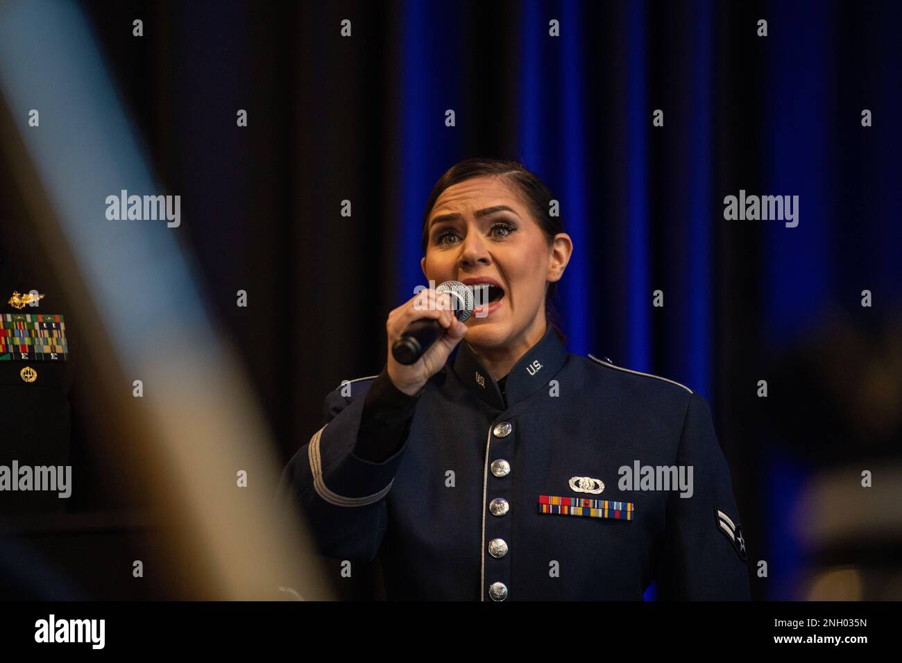 U.S. Air Force Airman 1st Class Ashley Huseby, Air Mobility Command’s Band of the Golden West vocalist, sings the Star-Spangled Banner during a ceremony presided by Air Force Chief of Staff Gen. CQ Brown, Jr. promoting retired Col. Clarence E. “Bud” Anderson to the honorary rank of Brigadier General at the Aerospace Museum of California in McClellan, California, Dec. 2, 2022. The ceremony was an opportunity to honor the 100-year-old World War II triple ace during the 75th anniversary year of the U.S. Air Force’s establishment as a military service. Stock Photo